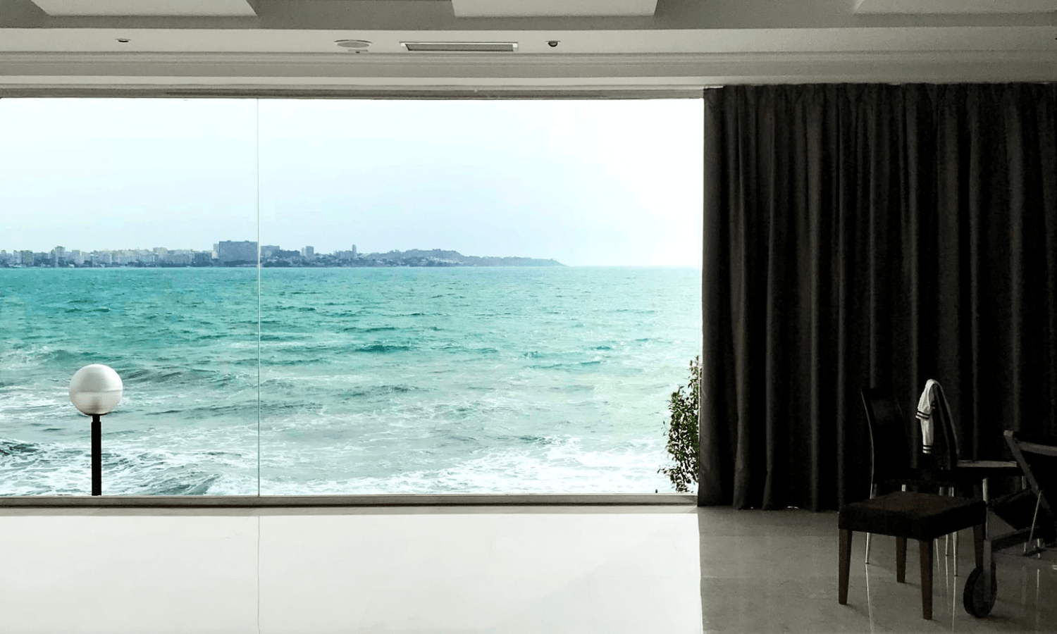 sala de estar com envidraçamento e vista para o mar