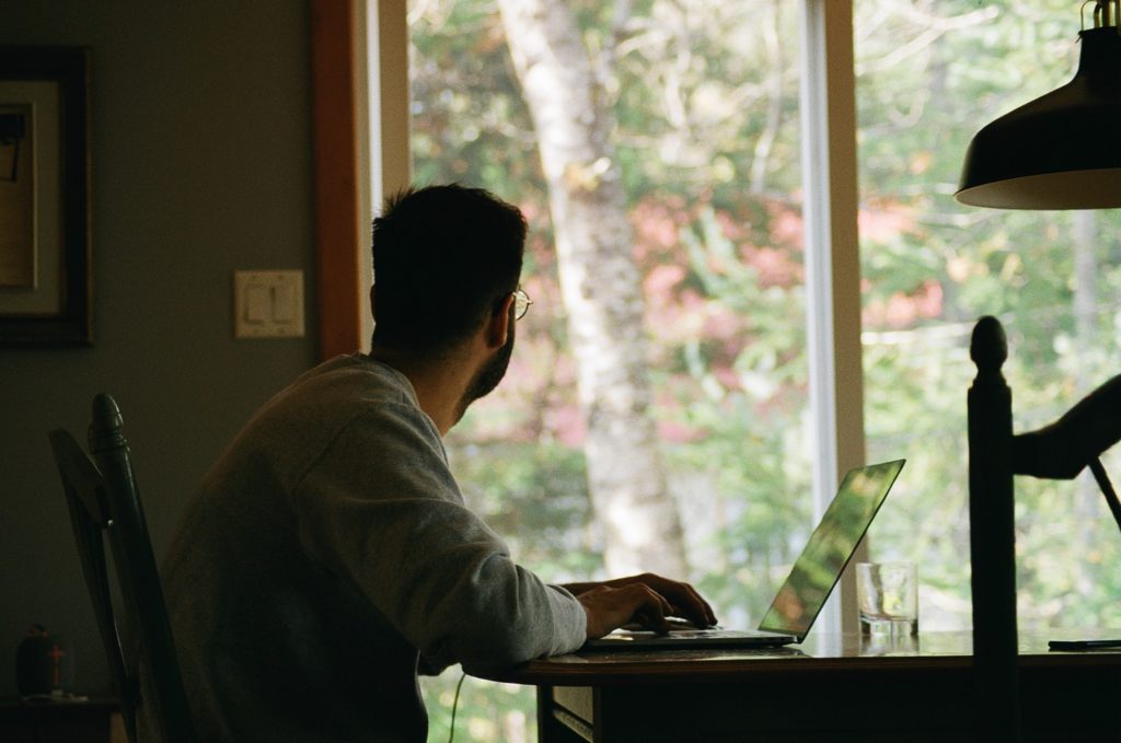 home office: homem no computador olhando para a janela