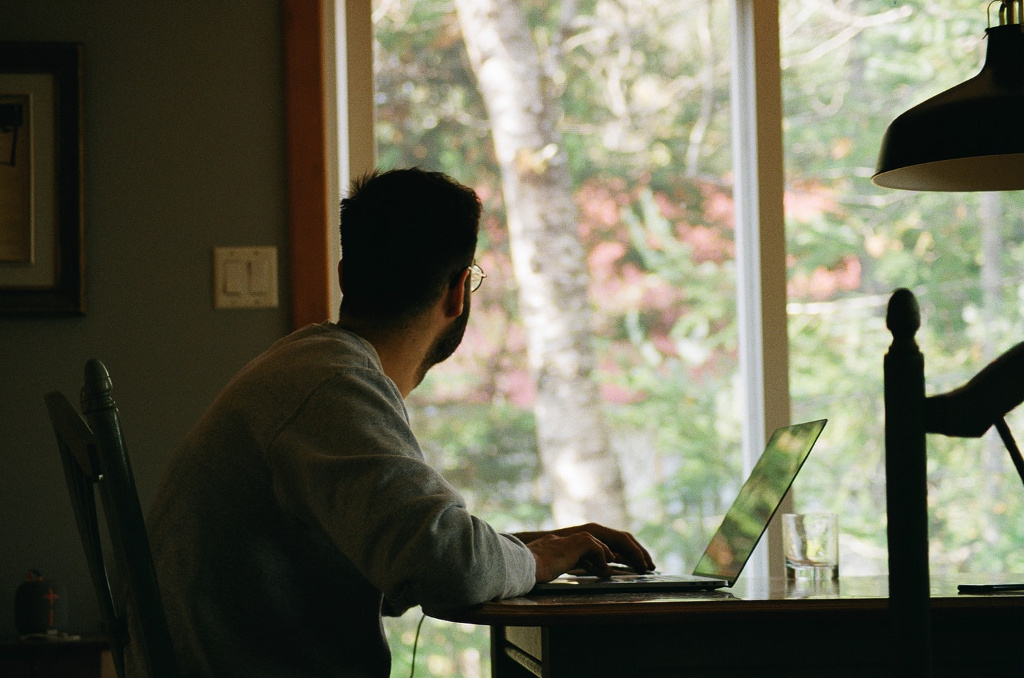 home office: homem no computador olhando para a janela