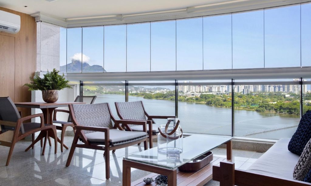 sala de estar com sacada com vidro e vista para a cidade